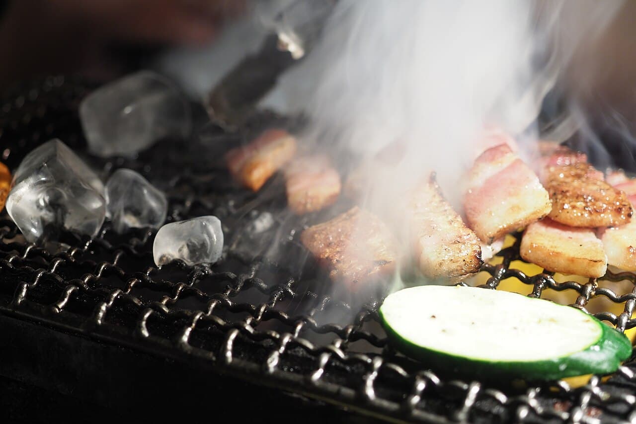 Slices of marinated beef grilling on a tabletop yakiniku grill